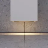 Lille, stilfuldt badeværelse med mørkeblå vægge, bløde gule badeværelsesmøbler med riller, og elegant rundt spejl med lampe