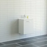 Badeværelse med skrå loft inspiration med lille hvidt vaskeskab samt højskab med runde sorte greb, samt smukt rundt spejl, orange fliser giver et friskt og moderne udtryk.