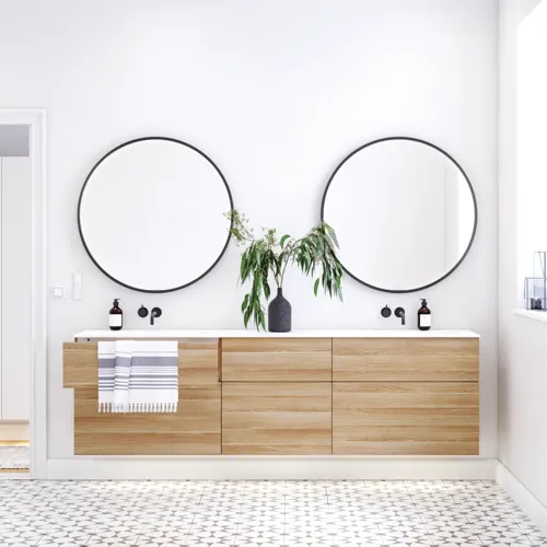 Nordisk badeværelse i træ med flotte runde spejle med sort kant og masser af opbevaring i badeværelsesmøblet