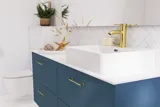 Badeværelse inspiration med badeværelsesmøbler i moderne blå farve, elegant bordstående vask og stort firkantet spejl med lys, hvide sildebensfliser giver et stilfuldt og klassisk udtryk
