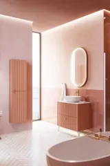 Stort vintage badeværelse med terracottafarvet vaskeskab, bordstående håndvask, ovalt spejl med messingkant, lyserøde og grå fliser giver et romantisk, feminint look