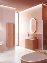 Stort vintage badeværelse med terracottafarvet vaskeskab, bordstående håndvask, ovalt spejl med messingkant, lyserøde og grå fliser giver et romantisk, feminint look