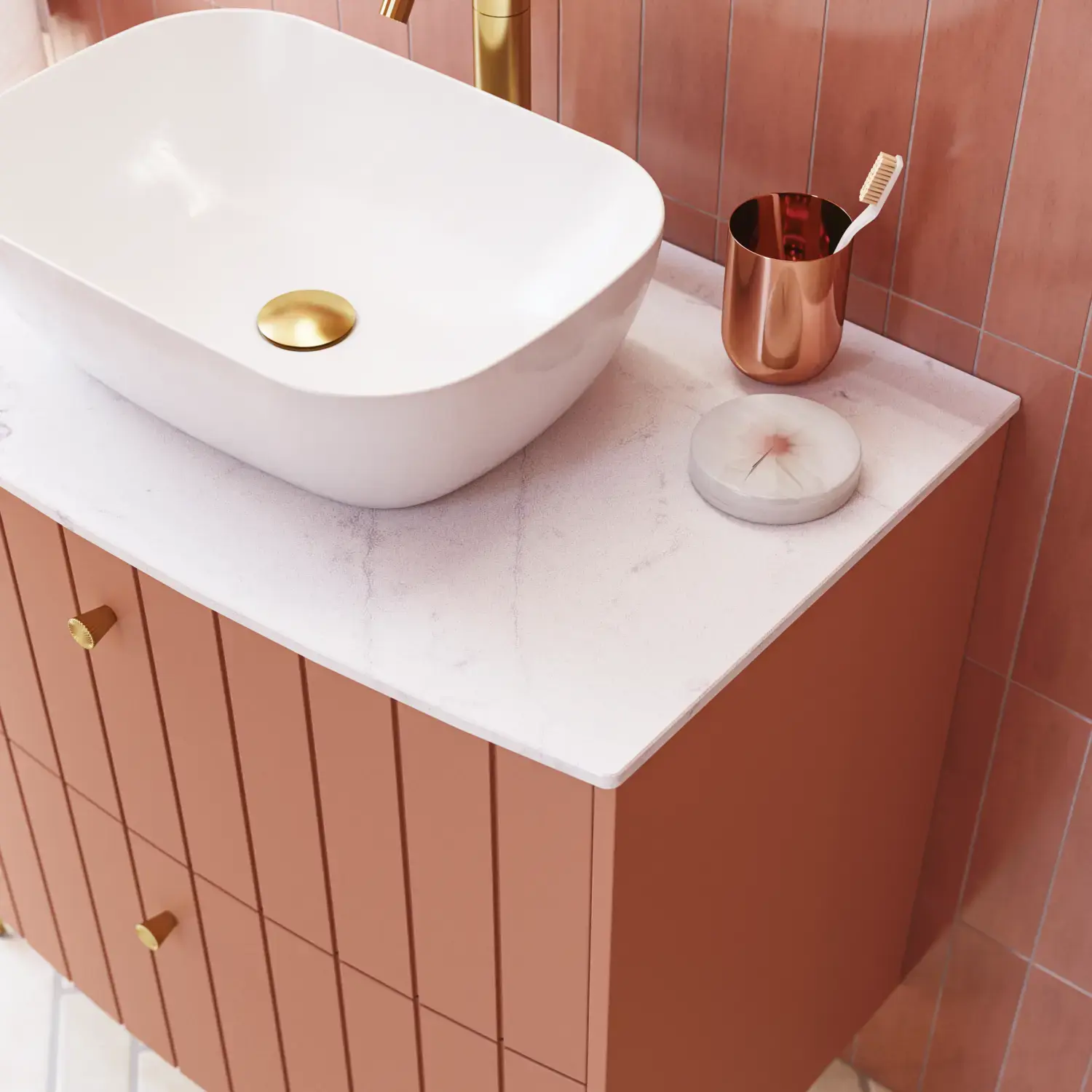 Stort vintage badeværelse med terracottafarvet vaskeskab, bordstående håndvask, ovalt spejl med messingkant, lyserøde og grå fliser giver et romantisk, feminint look