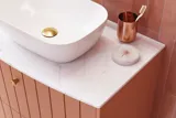 Stort vintage badeværelse med terracottafarvet vaskeskab, bordstående håndvask, ovalt spejl med messingkant, lyserøde og grå fliser giver et romantisk, feminint look