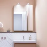 Lille badeværelse inspiration med lille vaskeskab i specialfarve med integreret greb, spejlskab med lamper, dekorationsspejl med tonet glashylde, hvide sildebensfliser på væggen giver et stilrent og klassisk udtryk.