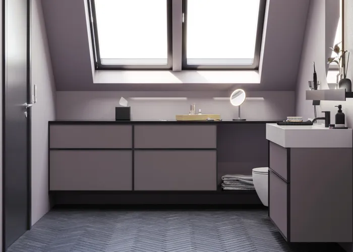Badeværelse med skrå vægge inspiration, med badeværelsesmøbler i lilla med elegante rammefronter, flot ovalt spejl med lampe, smuk og praktisk hylde, samt lillamalet væg og gråt sildebensgulv, der giver et elegant og moderne udtryk.