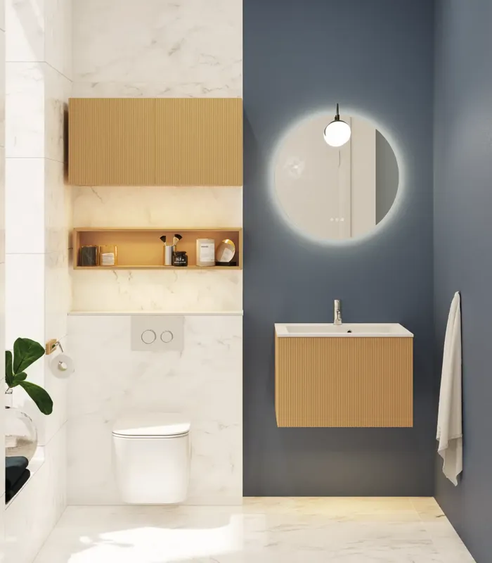 Lille, stilfuldt badeværelse med mørkeblå vægge, bløde gule badeværelsesmøbler med riller, og elegant rundt spejl med lampe