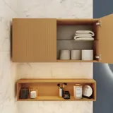 Lille stilfuldt badeværelse med mørkeblå vægge, bløde gule badeværelsesmøbler med riller, og elegant rundt spejl med lampe