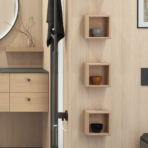 Stilfuldt badeværelse i skandinavisk og japandi indretningsstil med lyse trævægge, rundt spejl og minimalistiske badeværelsesmøbler