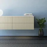 Badeværelse med skrå loft inspiration, beige badeværelsesmøbler med rifler, elegant bordplade samt firkantet bordstående håndvask, smukt firkantet spejl med stilfulde hylder, blå vægge, store vinduer og sort sildebensgulv giver et lyst og urban udtryk.