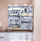 Lille badeværelse inspiration med lille vaskeskab i specialfarve med integreret greb, spejlskab med lamper, dekorationsspejl med tonet glashylde, hvide sildebensfliser på væggen giver et stilrent og klassisk udtryk.