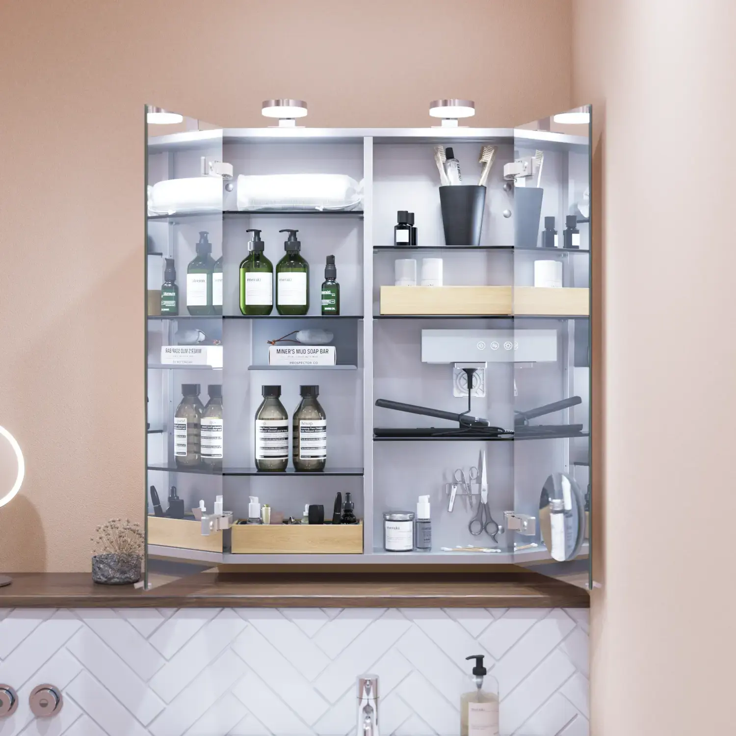 Lille badeværelse inspiration med lille vaskeskab i specialfarve med integreret greb, spejlskab med lamper, dekorationsspejl med tonet glashylde, hvide sildebensfliser på væggen giver et stilrent og klassisk udtryk.