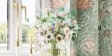 Badeværelse inspiration med grønne møbler i specialfarve med sider i natur eg, elegante riller, stilfuld bordplade med romantisk oval håndvask, smukt ovalt spejl og blomstret tapet giver et yndefuldt, vintage retro udtryk.