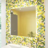 Badeværelse inspiration med badeværelsesmøbler i grå mat med elegant håndvask, smukt firkantet spejl, gråt gulv og små fliser i forskellige gule og grønne nuancer, der med gul væg giver et lyst og legende udtryk