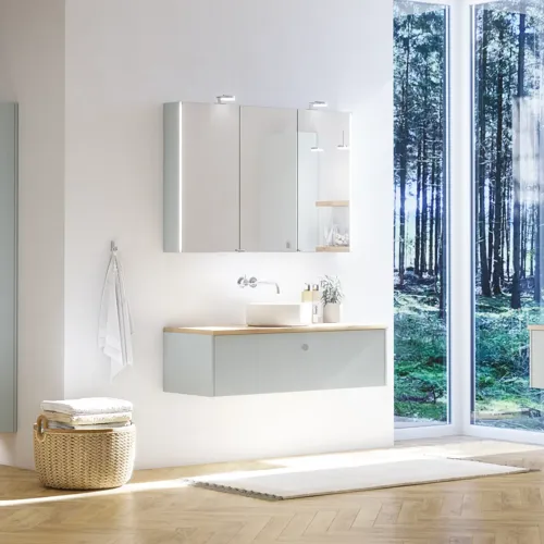 Stort badeværelse inspiration i nordisk stil med badeværelsesmøbler i lys blå farve og træbordplade med elegant bordstående håndvask, sildebensgulv i træ, der skaber en lys og klassisk stil