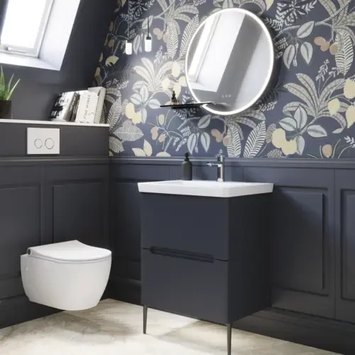 Badeværelse inspiration med mørkeblå vægpaneler, romantisk blomstret tapet, mørkeblåt vaskeskab med bløde former og et smukt rundt spejl med lys, der skaber et vintage udtryk