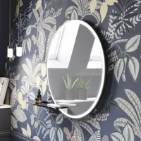 Badeværelse inspiration med mørkeblå vægpaneler, romantisk blomstret tapet, mørkeblåt vaskeskab med bløde former og et smukt rundt spejl med lys, der skaber et vintage udtryk