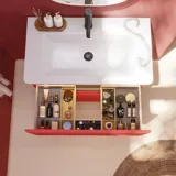 Badeværelse inspiration med røde vægge, blødt formede røde vaskeskabe og højskab, elegant hvid håndvask og smukt ovalt spejl med lys, der sammen med de naturlige omgivelser skaber et vintage udtryk