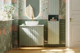 Badeværelse inspiration med grønne møbler i specialfarve med sider i natur eg, elegante riller, stilfuld bordplade med romantisk oval håndvask, smukt ovalt spejl og blomstret tapet giver et yndefuldt, vintage retro udtryk.