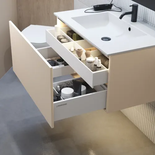 Stilfuld badeværelse inspiration med beige vaskeskab med inderskuffe, overskab, åben reol, oval spejl med belysning, matchende pendler, hylde under spejlet, og væghængt toilet. Vægge med lyse, aflange fliser
