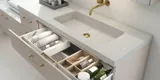 Lyst og lækkert badeværelse med brusehjørne og bordplade i sten