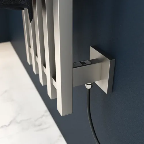 Elektrisk håndklædetørre på mørkeblå væg i stilfuldt badeværelse.