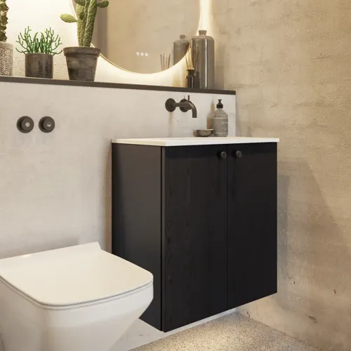 Badeværelse inspiration med vaskeskab i sort eg samt elegant rundt spejl og håndvask, lækkert tilbehør samt kaktusplanter og vægge i rå materialer giver et råt, industrielt og urban look.