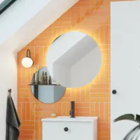 Badeværelse med skrå loft inspiration med lille hvidt vaskeskab samt højskab med runde sorte greb, samt smukt rundt spejl, orange fliser giver et friskt og moderne udtryk.