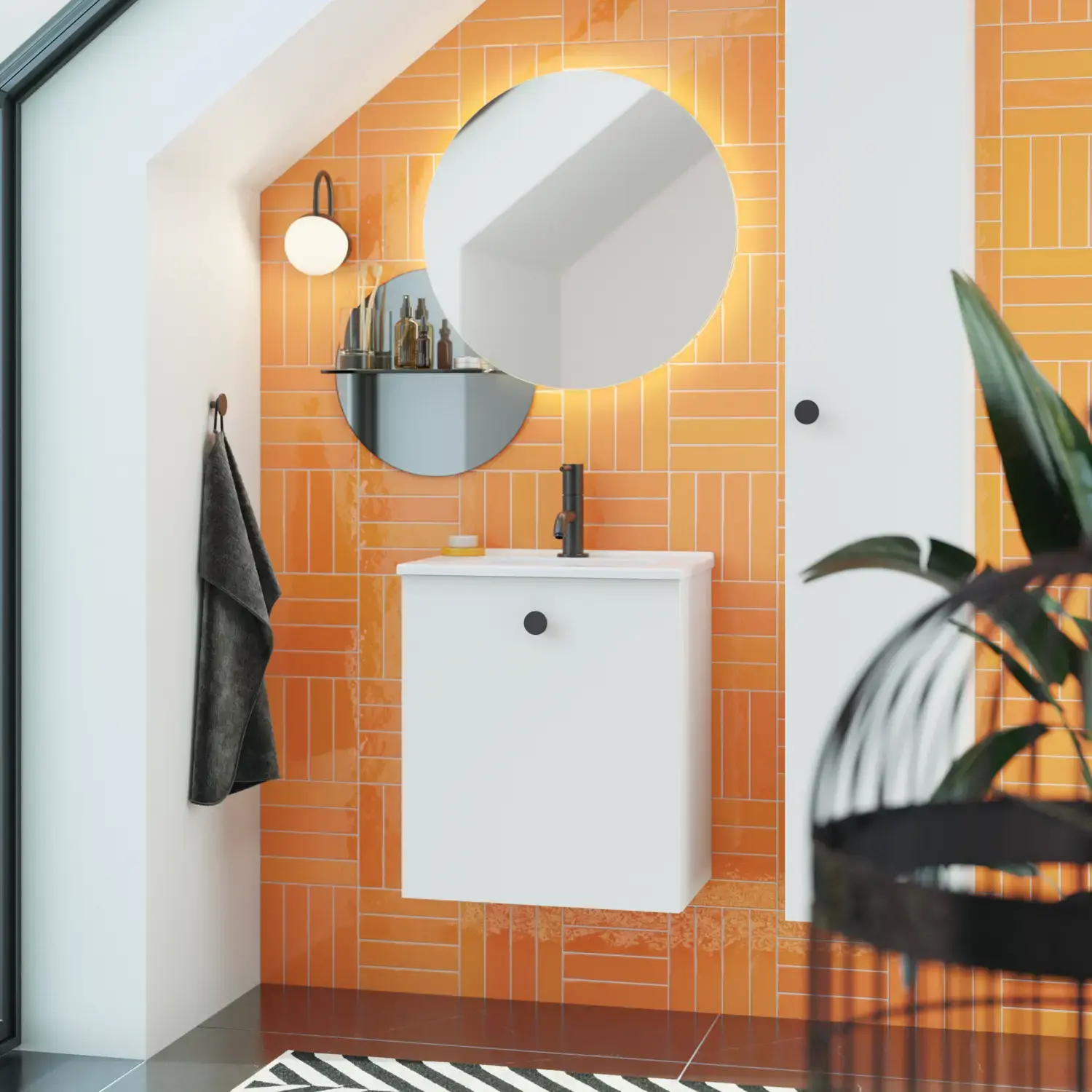 Badeværelse med skrå loft inspiration med lille hvidt vaskeskab samt højskab med runde sorte greb, samt smukt rundt spejl, orange fliser giver et friskt og moderne udtryk.