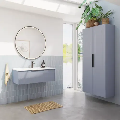 Badeværelse inspiration med aflange lyseblå fliser og betongulv, elegant vaskeskab i lys blå og smukke smalle striber, stilren og tynd håndvask, dobbelt højskab med smukke smalle striber, samt minimalistisk rundt spejl med sort kant og lys.