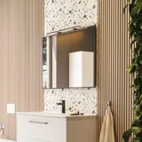 Stort badeværelse inspiration med badeværelsesmøbler i mat hvid med elegant håndvask samt firkantet spejl med sort kant og lampe, terrazzo væg- og gulv samt planter på væggen giver et moderne og sofistikeret udtryk.