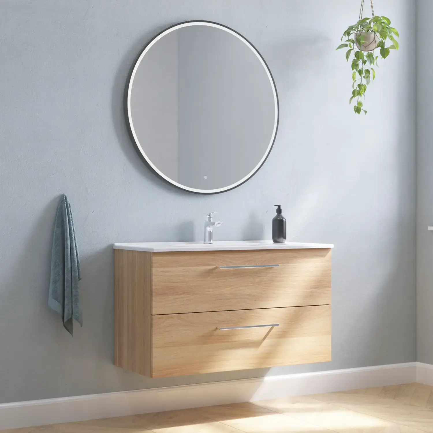 Stort badeværelse inspiration med vaskeskab i Varm Eg med elegant håndvask, krom greb og smukt rundt spejl med sort kant og lys, sildebensgulv og grå vægge giver et moderne udtryk.