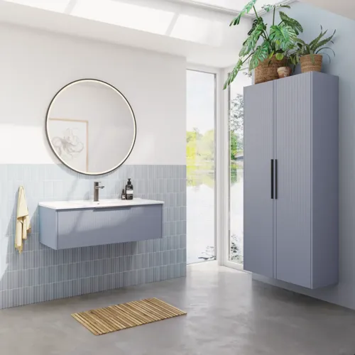Badeværelse inspiration med aflange lyseblå fliser og betongulv, elegant vaskeskab i lys blå og smukke smalle striber, stilren og tynd håndvask, dobbelt højskab med smukke smalle striber, samt minimalistisk rundt spejl med sort kant og lys.