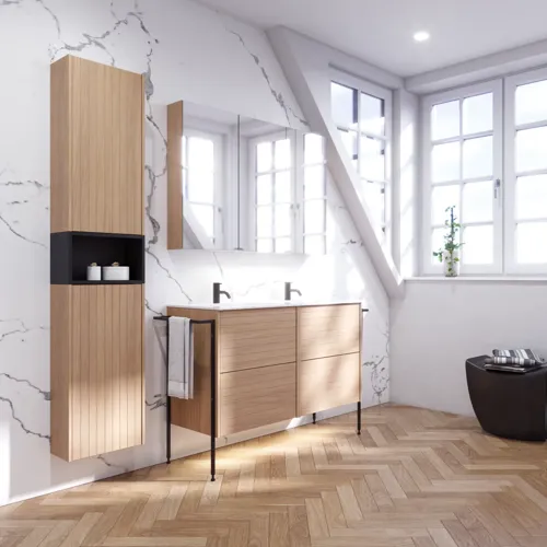 Badeværelse inspiration med vaskeskabe samt overskabe i lys eg med lameller, elegant dobbelt håndvask, smukt spejlskab med lys, sildebensgulv i lys træ og hvid marmorvæg giver et klassisk, lyst og stilrent udtryk.
