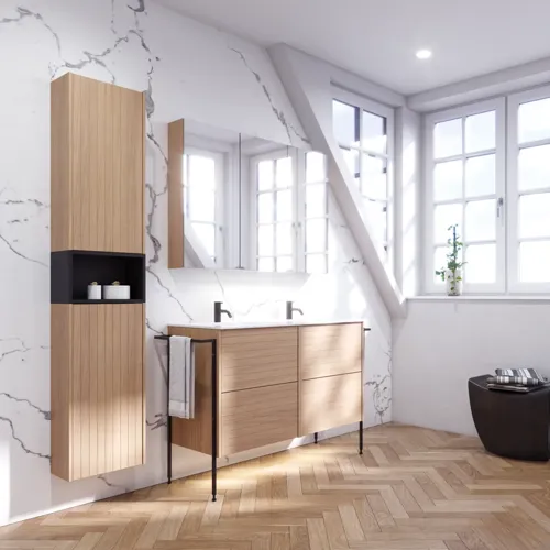 Badeværelse inspiration med vaskeskabe samt overskabe i lys eg med lameller, elegant dobbelt håndvask, smukt spejlskab med lys, sildebensgulv i lys træ og hvid marmorvæg giver et klassisk, lyst og stilrent udtryk.