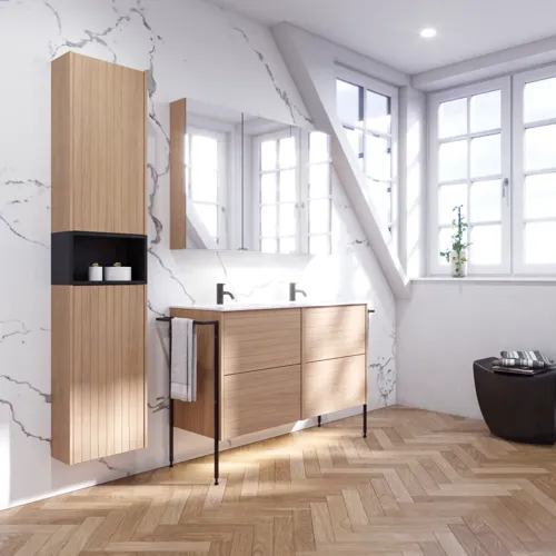 Badeværelse inspiration med vaskeskabe samt overskabe i lys eg med lameller, elegant dobbelt håndvask, smukt spejlskab med lys, sildebensgulv i lys træ og hvid marmorvæg giver et klassisk, lyst og stilrent udtryk.