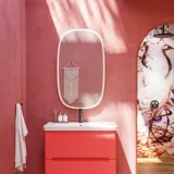 Badeværelse inspiration med røde vægge, blødt formede røde vaskeskabe og højskab, elegant hvid håndvask og smukt ovalt spejl med lys, der sammen med de naturlige omgivelser skaber et vintage udtryk